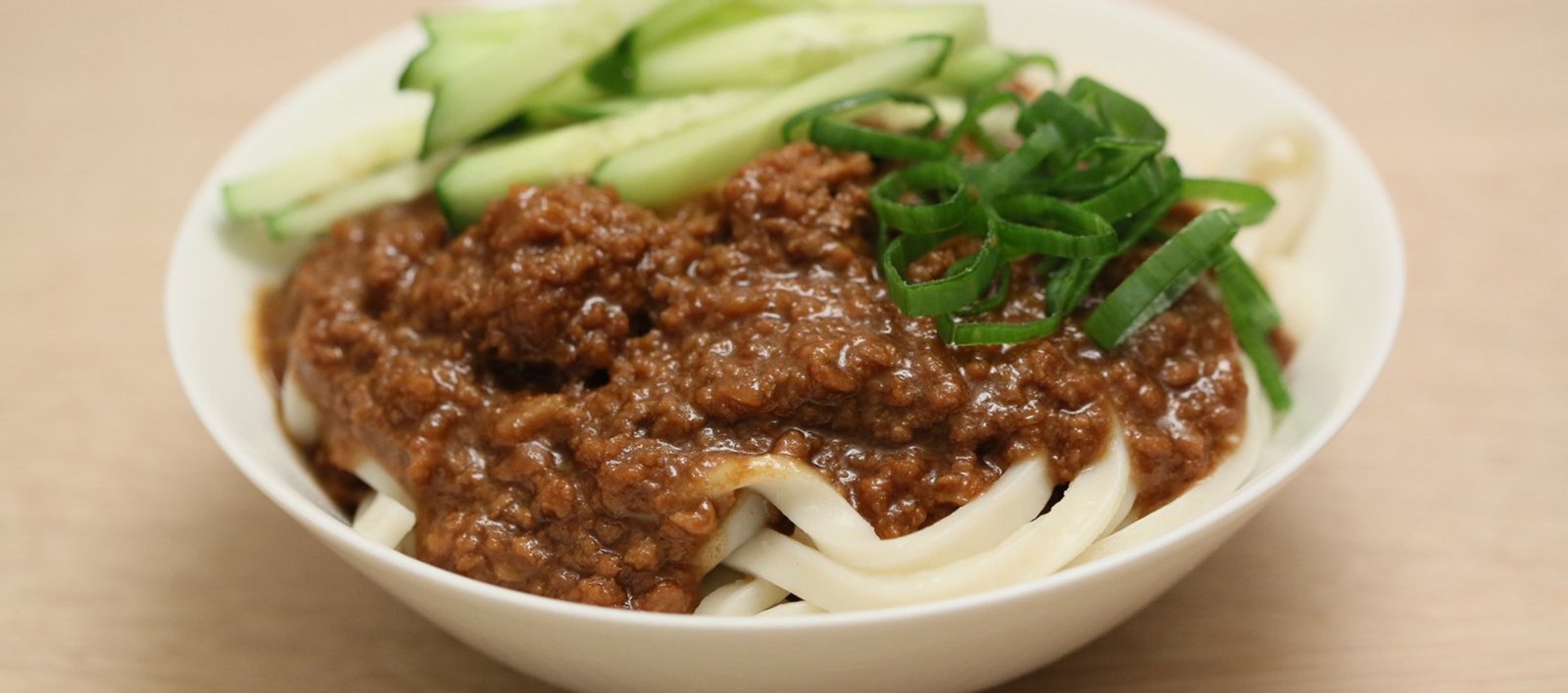 A bowl of noodles topped with savoury mince and greens